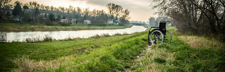 wheelchair isolated in a field by the river