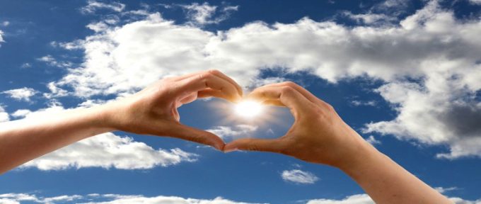 heart symbol with hand towards the sun in the sky