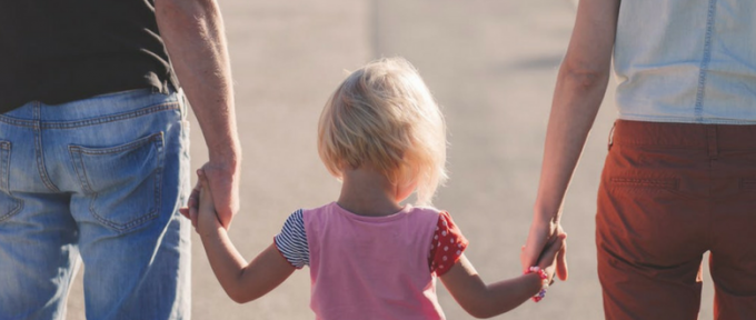 child holding parents hand walking