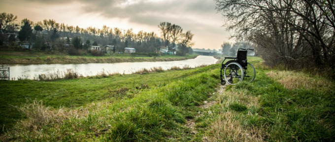 wheelchair isolated in a field by the river
