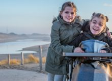 young girl in wheelchair on the beach with her friend