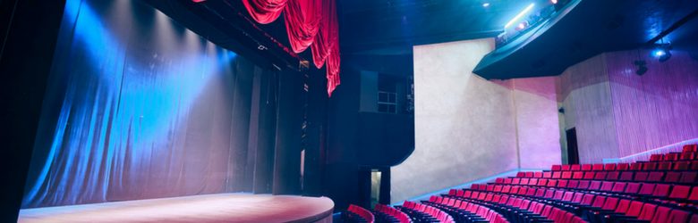 empty theatre seats and stage with dramatic lighting