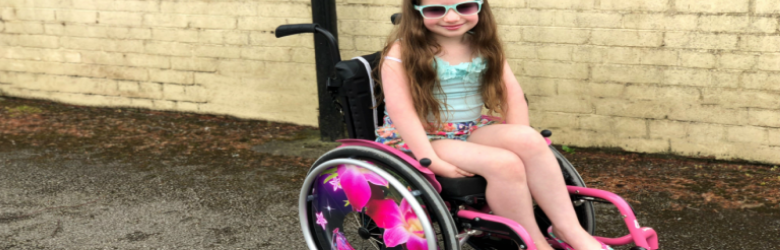 amelia wearing sunglasses smiling in her wheelchair