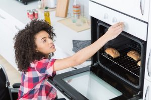 woman in wheelchair reaching oven knob