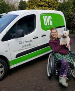 woman in wheelchair in front of van with her dog