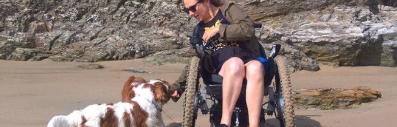 woman in wheelchair with 2 dogs on the beach