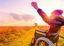 woman in wheelchair with her hands in the air outside