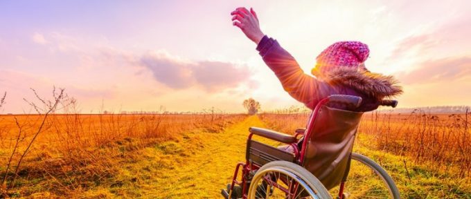 woman in wheelchair with her hands in the air outside