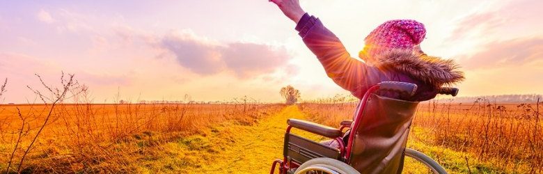 woman in wheelchair with her hands in the air outside