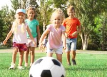 children running on grass playing with football