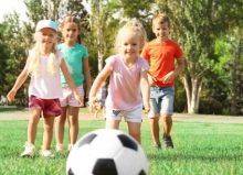 children running on grass playing with football