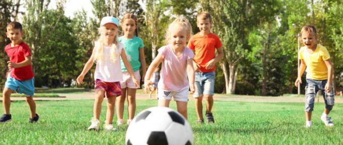 children running on grass playing with football