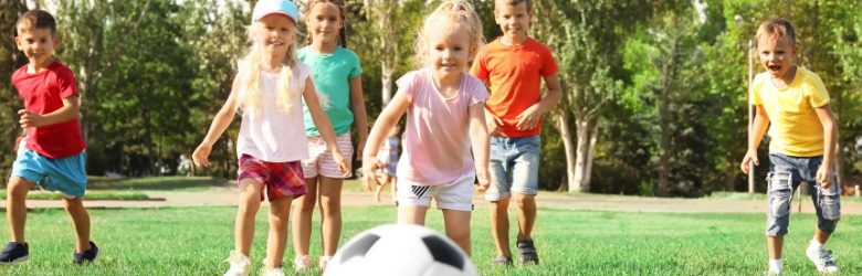 children running on grass playing with football