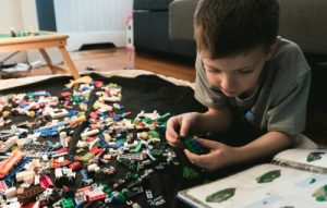 boy in grey playing with LEGO blocks