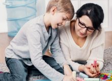 mother and autistic son playing with colouring chalks at home