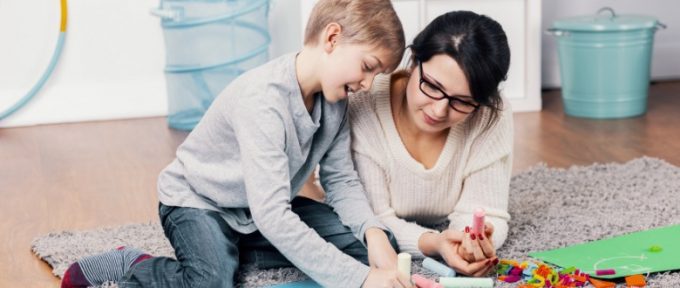 mother and autistic son playing with colouring chalks at home