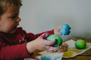 little boy painting easter eggs