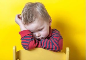 little boy with hand on his head looking down