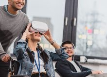 woman in wheelchair using virtual reality glasses at modern office