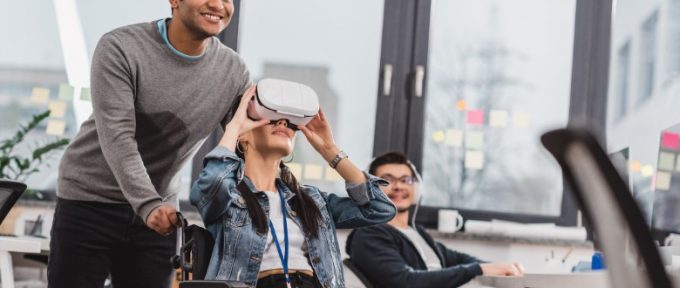 woman in wheelchair using virtual reality glasses at modern office