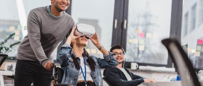 Frau im Rollstuhl mit Virtual-Reality-Brille im modernen Büro