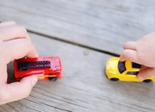 father's hand and child's hand playing with toy cars