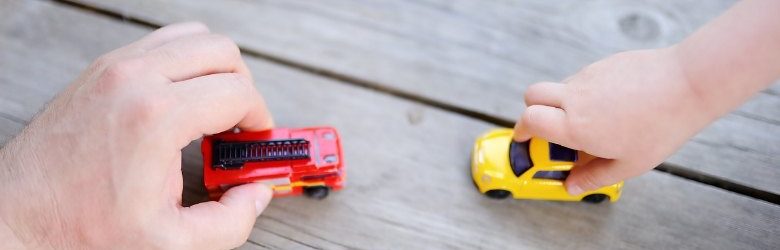 father's hand and child's hand playing with toy cars