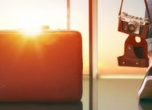 person looking out airport window with suitcase