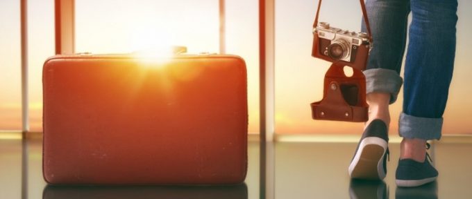 person looking out airport window with suitcase