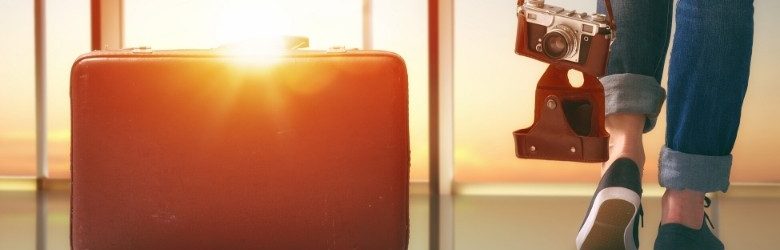 person looking out airport window with suitcase