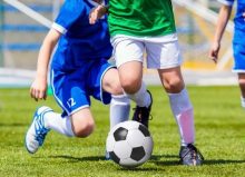 footballers kicking football on pitch