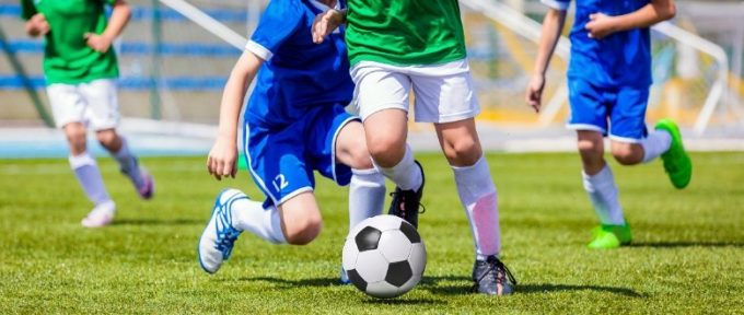 footballers kicking football on pitch