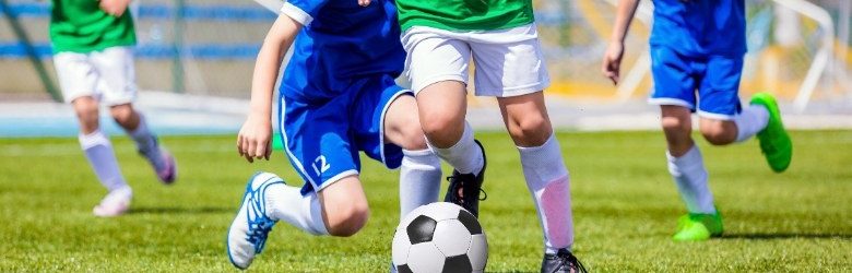 footballers kicking football on pitch