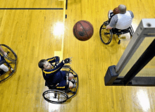 3 men playing wheelchair basketball