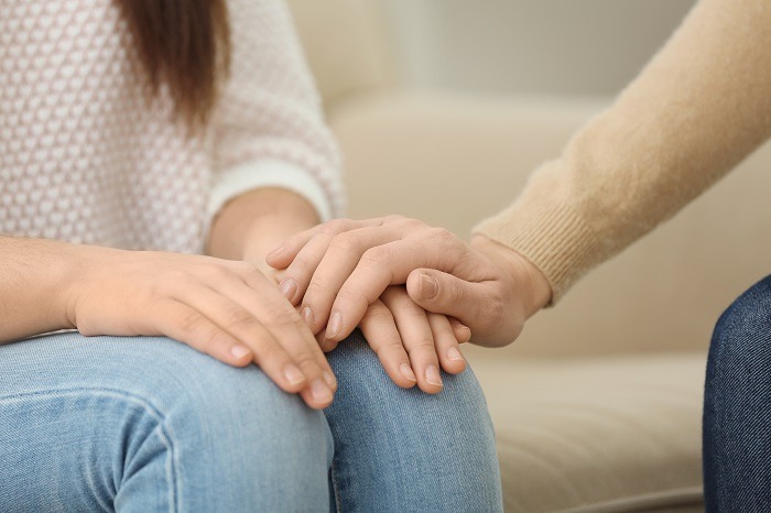 hand comforting a young woman