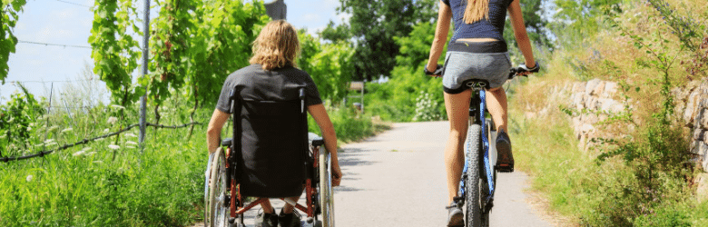 man in wheelchair with woman on bike doing some exercise